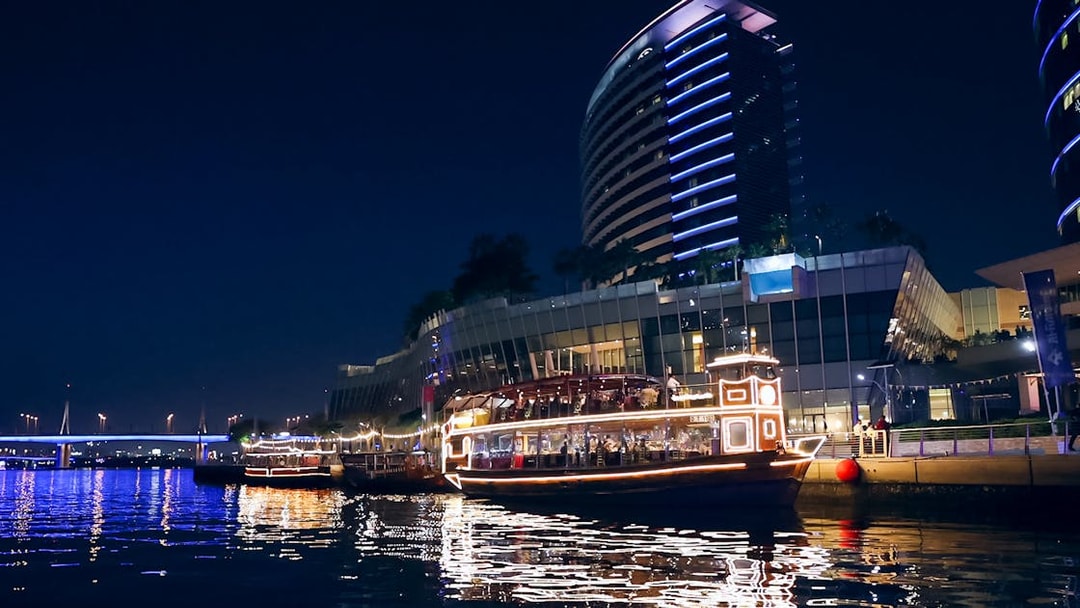 Dubai Canal cruise boat illuminated at night near modern buildings.