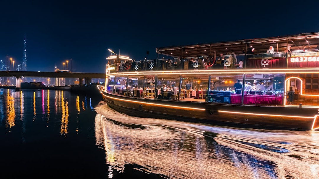 Dubai Canal cruise boat at night with city skyline in background.