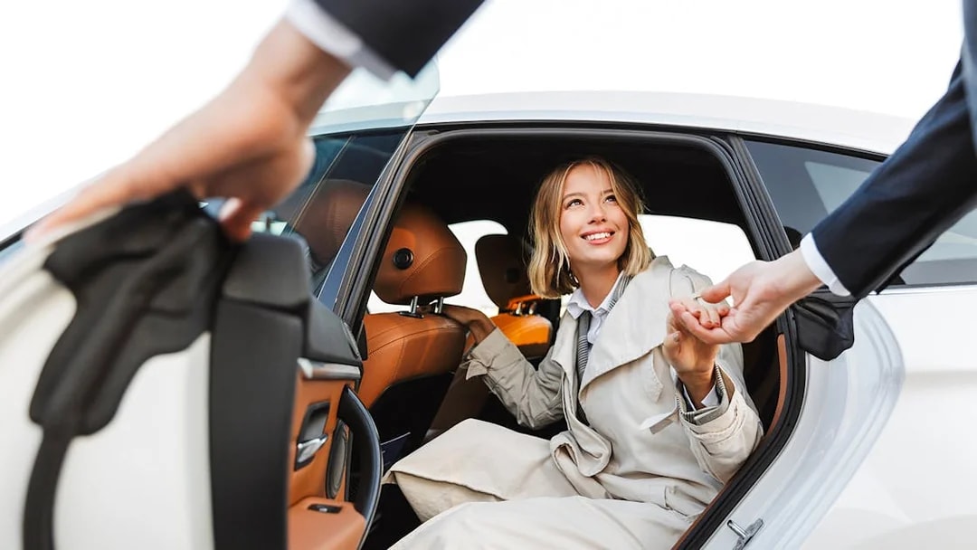 Woman exiting a car with assistance, smiling, during a tour transfer.