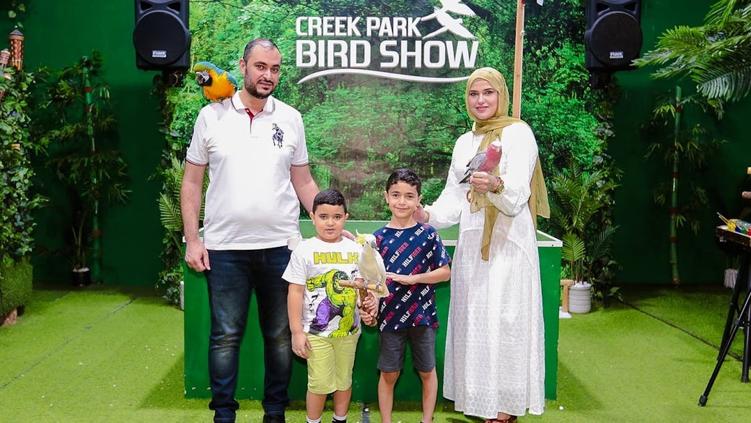 Family posing with parrots at Creek Park Bird Show.