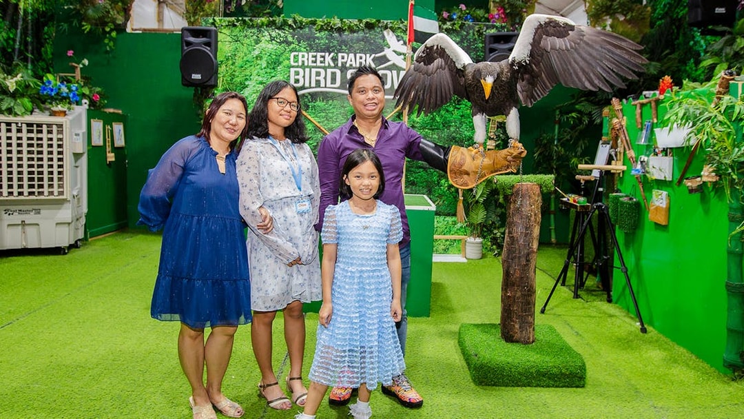 Tourists at Creek Park Bird Show posing with an eagle on a handler's glove.