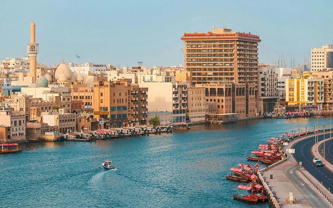 Dubai Creek with traditional boats and city skyline in the background.