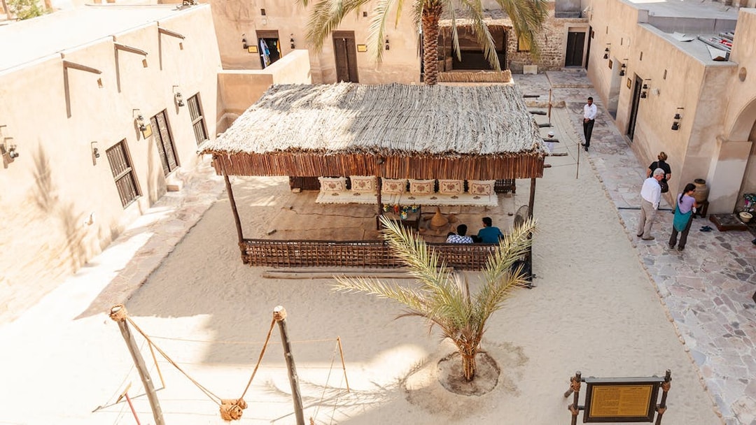 Traditional courtyard in Dubai with visitors and a shaded seating area.