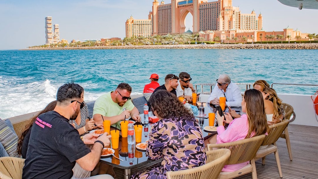Tourists dining on a Superyacht TriDeck Cruise with Atlantis The Palm in the background, Dubai.