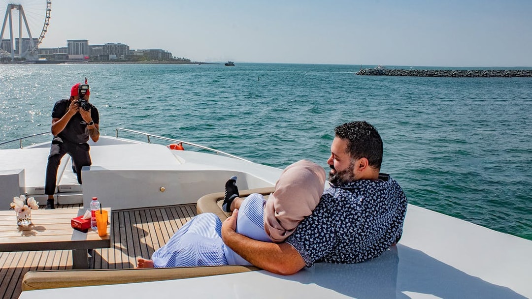 Tourists on Superyacht TriDeck Cruise taking photos with Dubai skyline in background.