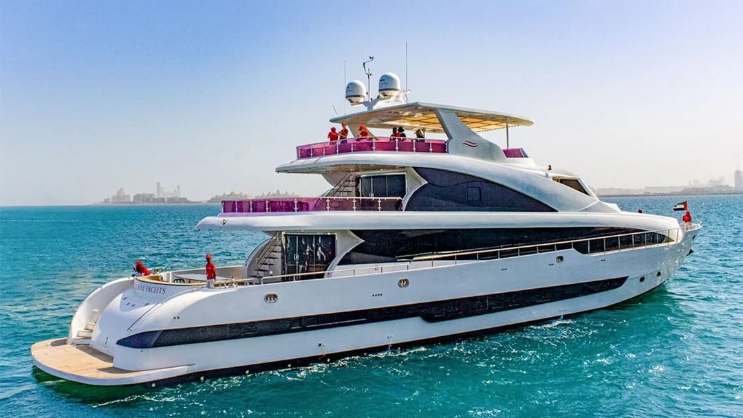 Superyacht TriDeck cruising in clear blue waters near a distant city skyline.
