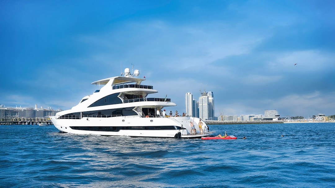 Superyacht TriDeck cruising near city skyline with people enjoying water activities.