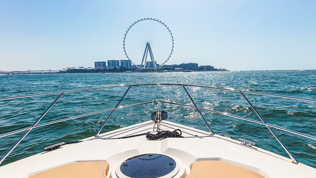 Luxury yacht cruising towards Ain Dubai on a sunny day.