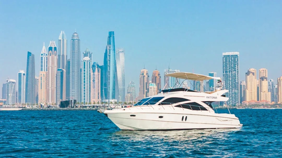 Private luxury yacht sailing in front of Dubai Marina skyline.