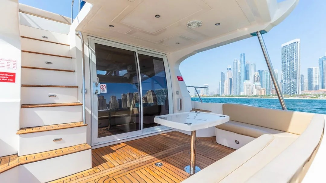 Private luxury yacht deck with Dubai skyline in the background.