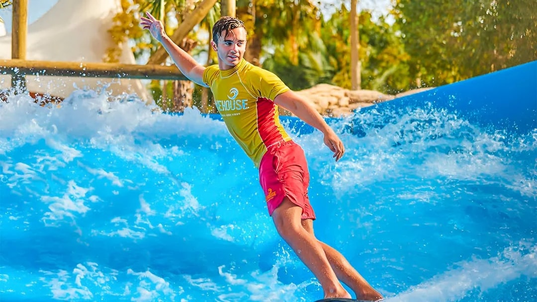 Surfer riding wave at Aquaventure Waterpark, Dubai.