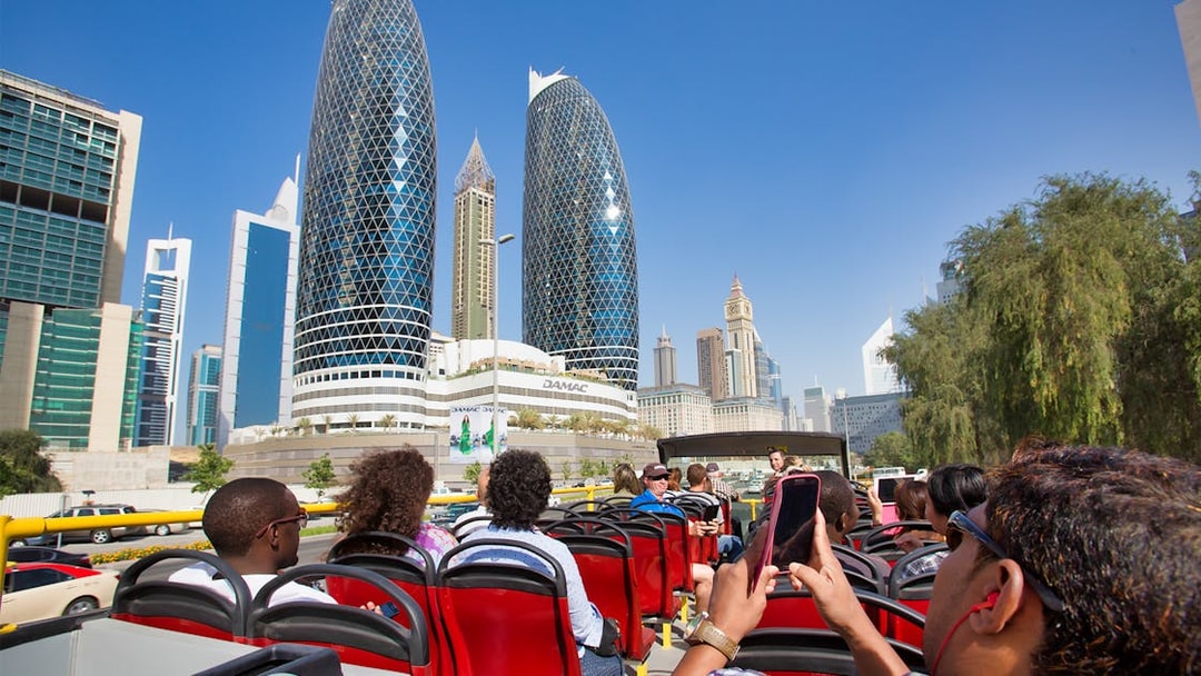Open-top bus tour in Dubai with view of modern skyscrapers and cityscape.