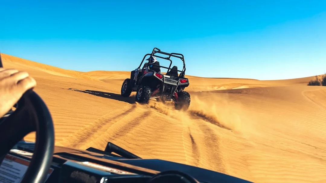 Quad biking adventure on desert dunes during a tour with hotel transfers and breakfast.