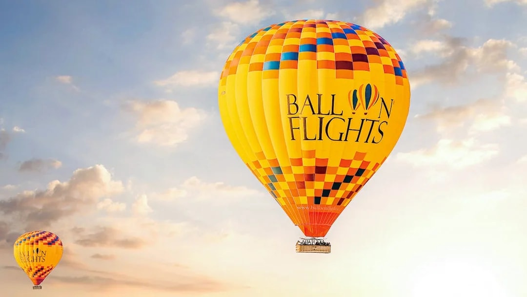 Hot air balloon in the sky during sunrise, part of a tour with hotel transfers, breakfast, camel ride, and quad biking.