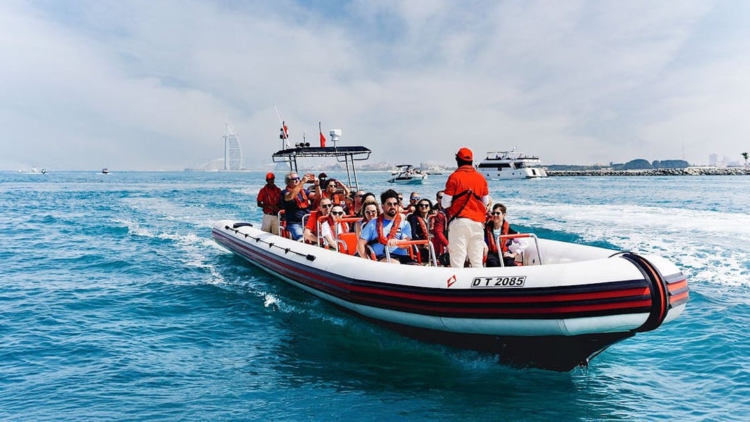 Speedboat tour with passengers near Dubai Marina, Burj Al Arab visible in the background.