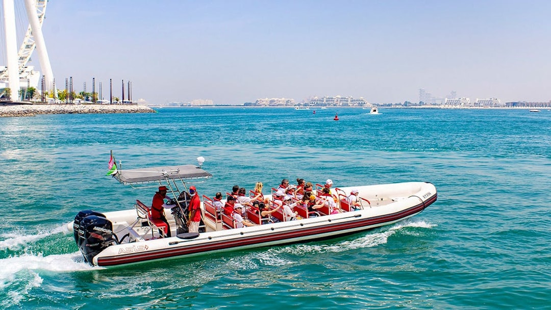 Speedboat with tourists cruising Dubai Marina near Ain Dubai.