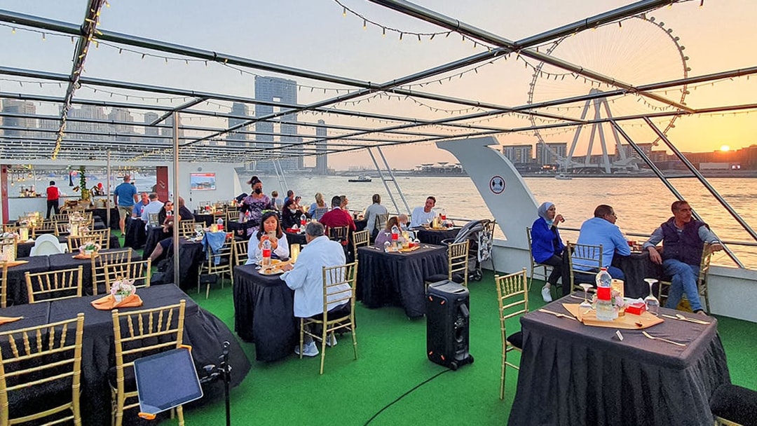 Guests dining on a sunset cruise in Dubai Marina with views of the Ferris wheel.
