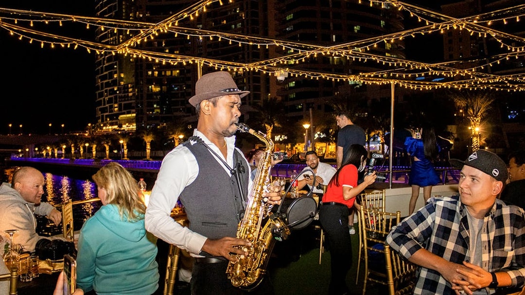 Saxophonist performing on a Dubai Marina sunset cruise with buffet dinner.