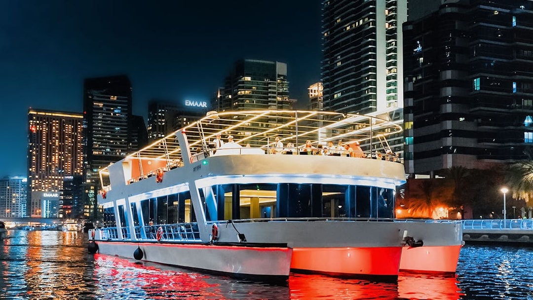 Sunset cruise boat with diners in Dubai Marina, skyscrapers illuminated in the background.