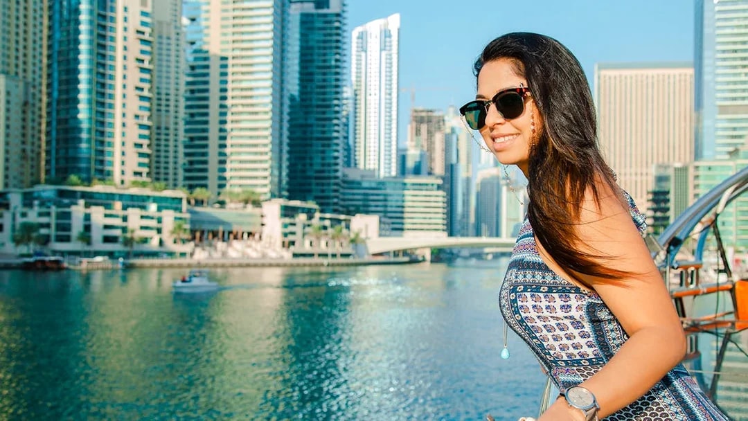 Woman enjoying a dhow cruise in Dubai Marina with skyscrapers in the background.