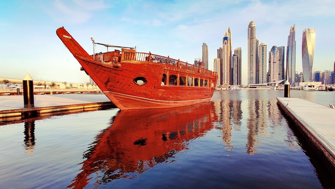 Traditional dhow boat docked at Dubai Marina with skyscrapers in the background.