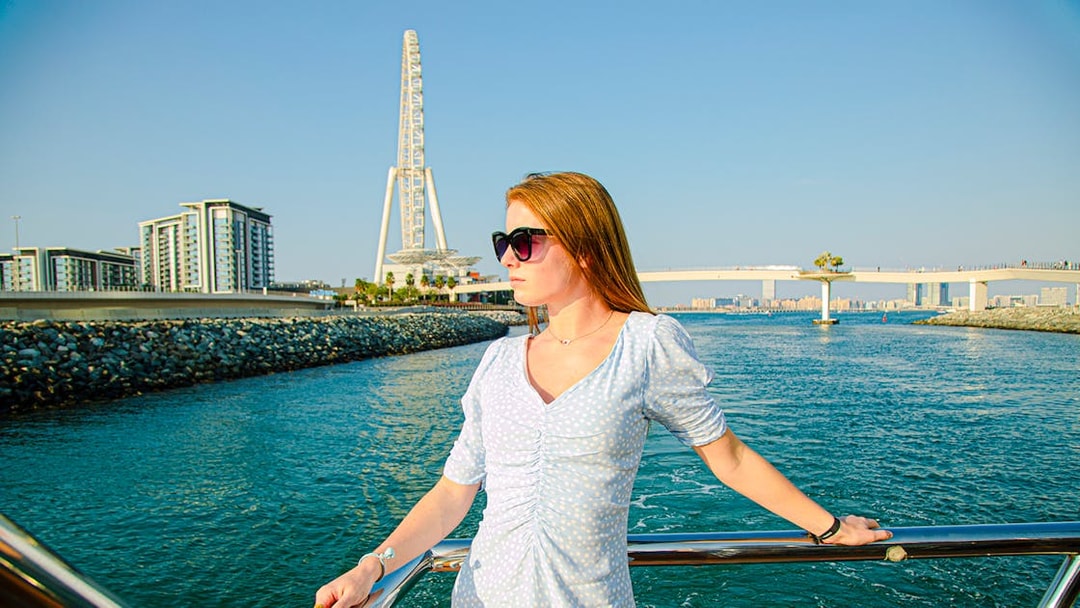 Woman on a dhow cruise in Dubai Marina with Ain Dubai in the background.