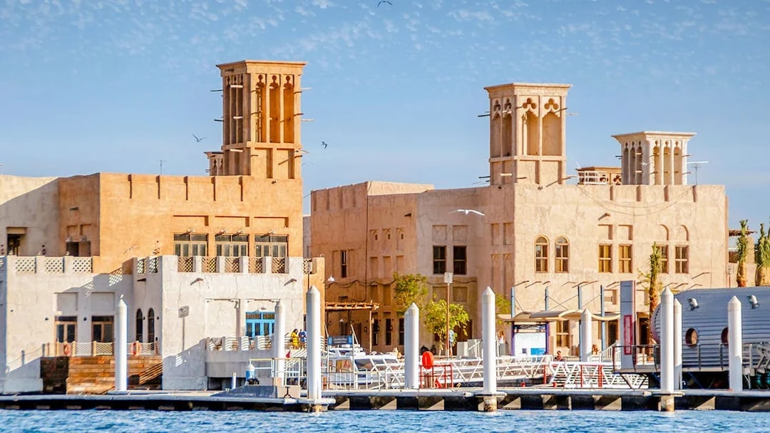 Traditional buildings along Dubai Creek with wind towers and waterfront view.