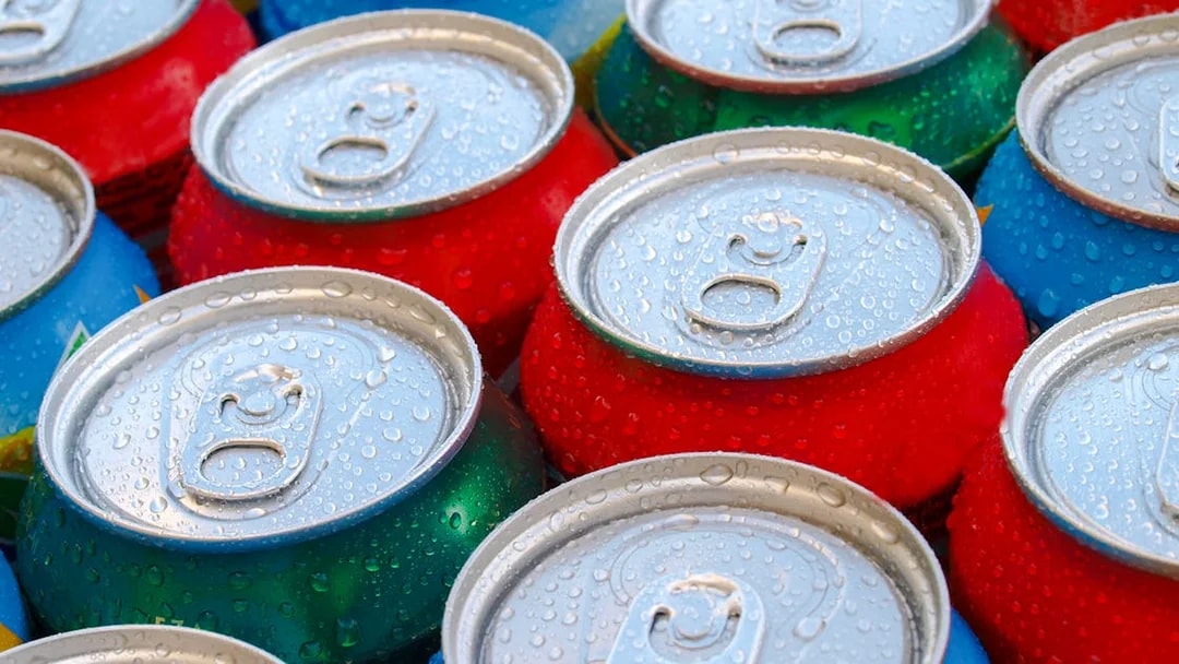 Cold soft drink cans with condensation droplets.