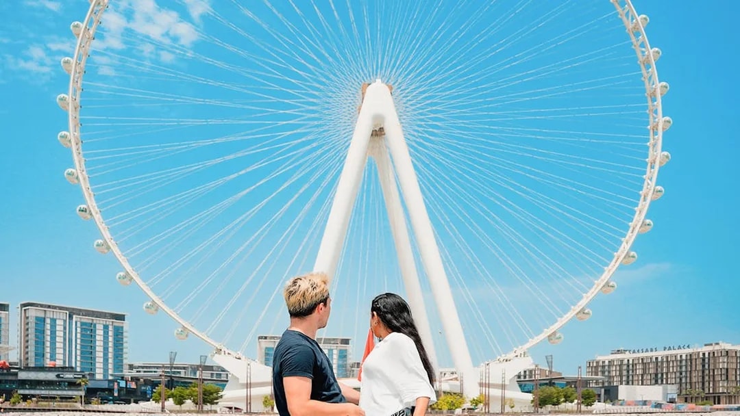 Couple viewing Ain Dubai Ferris wheel from waterfront.