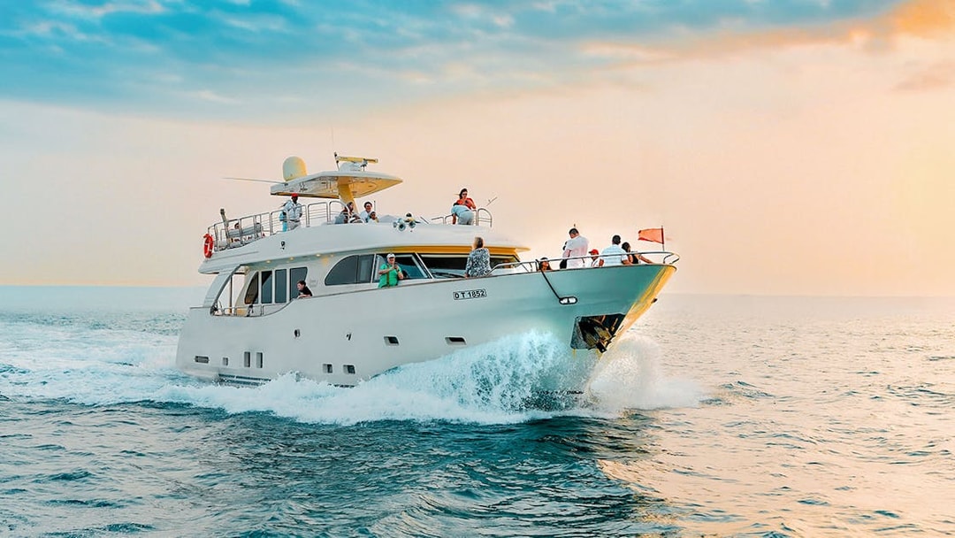 Yacht cruising on open water during sunset with passengers enjoying the view.