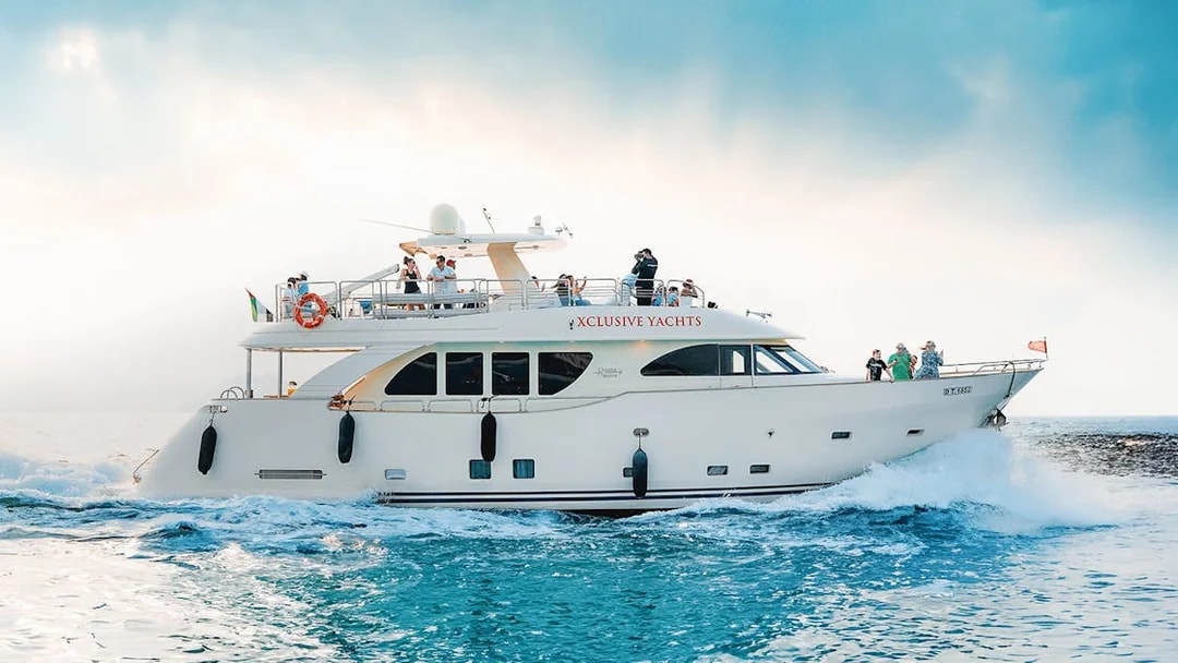 Luxury yacht cruising on blue waters with passengers enjoying the view.