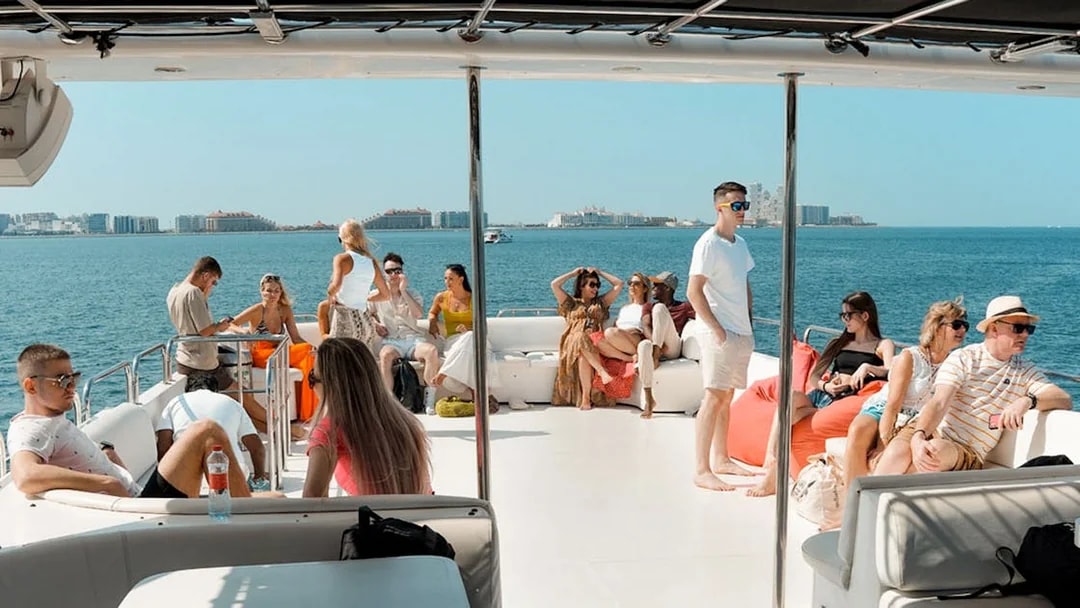 Tourists relaxing on a luxury yacht cruise with city skyline in the background.