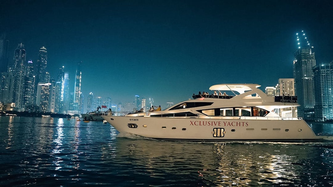 Luxury yacht cruising near Dubai Marina with city skyline in the background.
