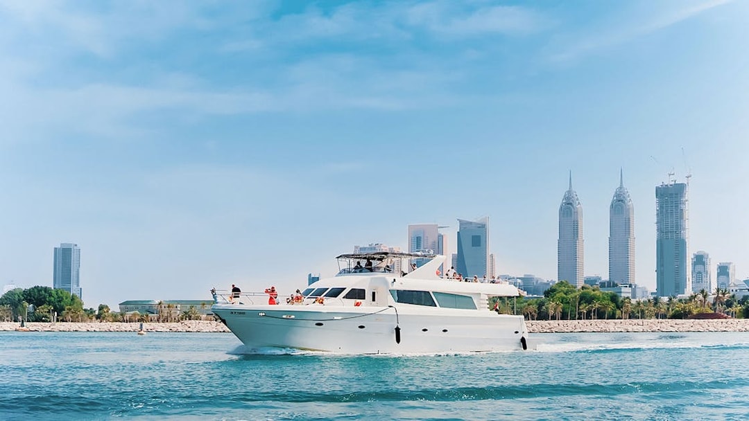 Luxury yacht cruising near Dubai Harbour with city skyline in the background.
