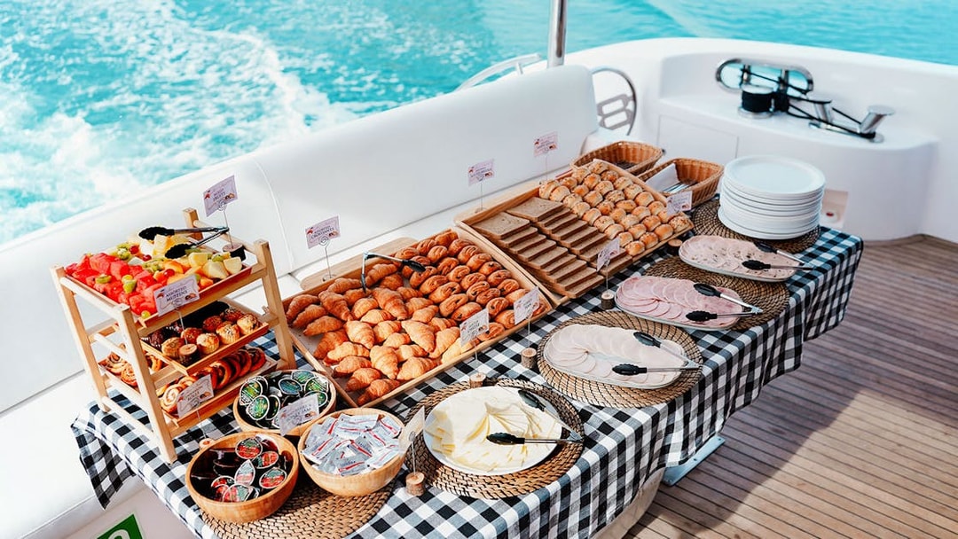 Breakfast buffet on luxury yacht cruise with pastries, fruits, and cold cuts.