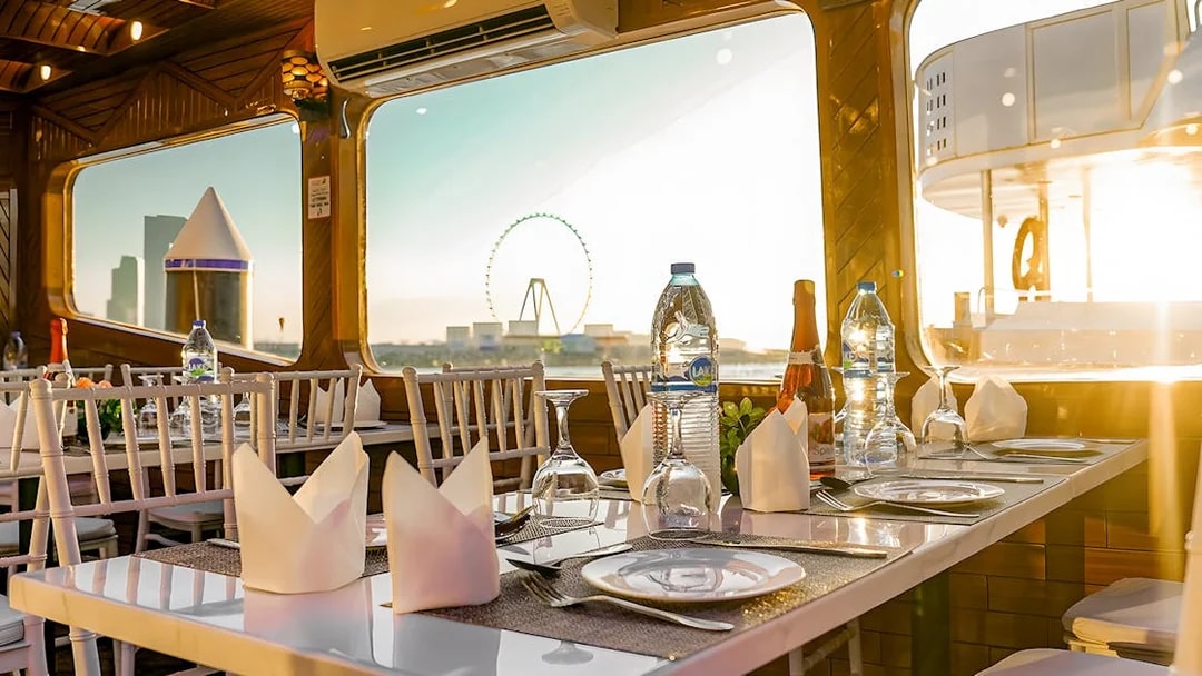 Dhow cruise dining setup with Dubai skyline and Ferris wheel view.