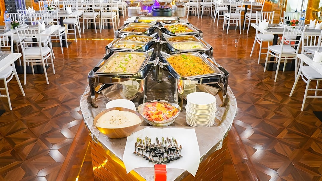Buffet setup on a dhow cruise in Dubai Marina with various dishes and dining tables.