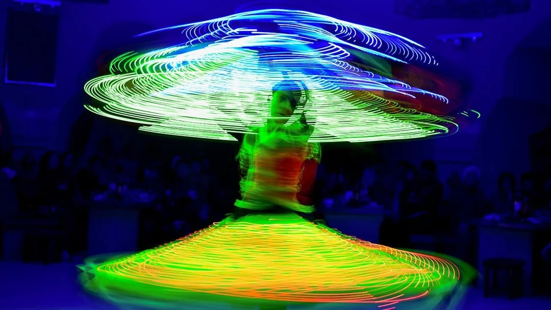 Tanoura dancer spinning with colorful lights on a cruise.