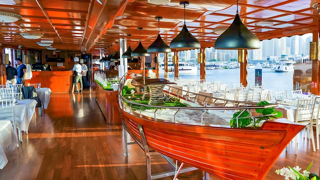 Luxury dhow dinner cruise setup with tables and Dubai Marina view.