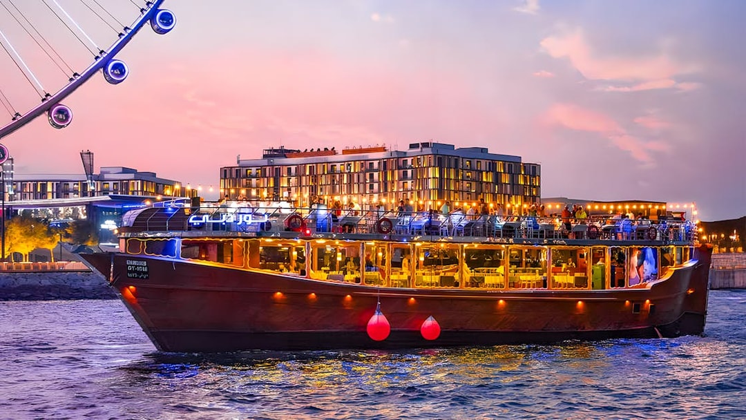 Luxury dhow cruise near Ain Dubai at sunset, with cityscape in the background.