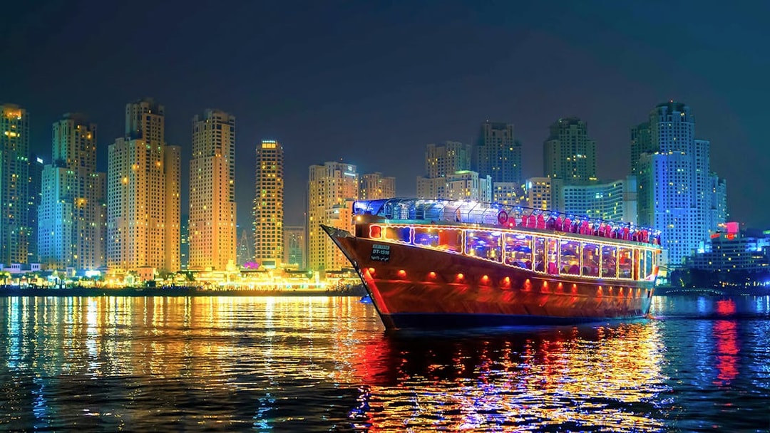 Luxury dhow cruise with lights on Dubai Marina at night, skyscrapers in the background.