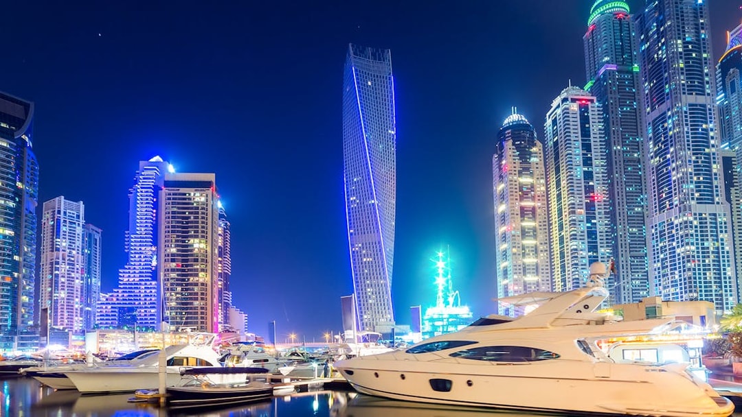 Cayan Tower illuminated at night with yachts in Dubai Marina.