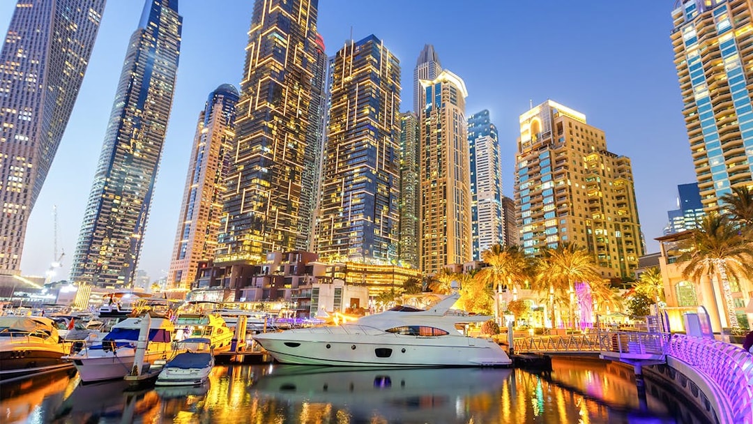 Dubai Marina skyline with yachts in the harbor at dusk.