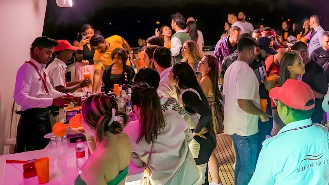 People enjoying drinks at an open bar on a party yacht in Dubai.