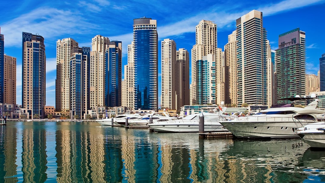 Yachts docked at Dubai Marina with skyscrapers in the background.