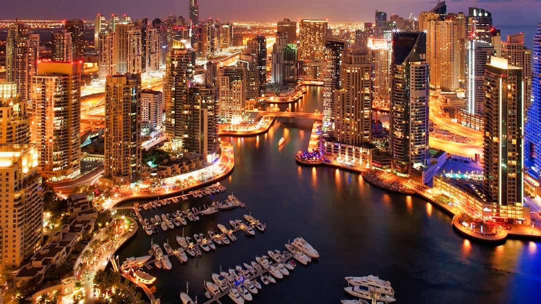 Dubai Marina skyline at night with illuminated skyscrapers and yachts, part of Dhow Cruise + Desert Safari combo.
