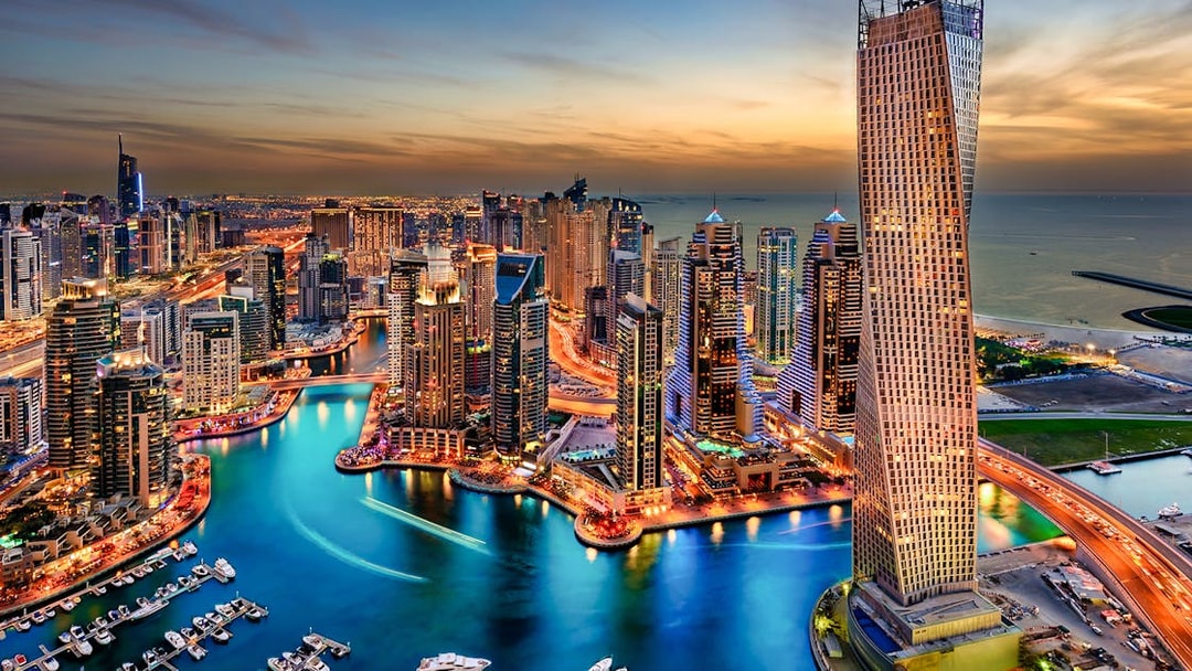 Dubai Marina skyline at sunset, view of skyscrapers and waterway.