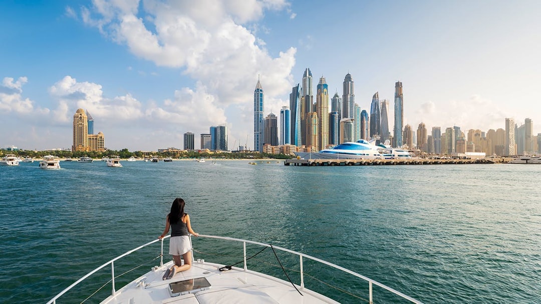 Yacht cruising in Dubai Marina with city skyline in the background.