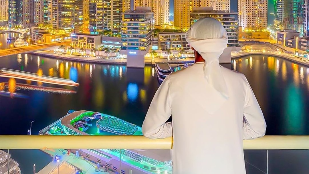 Person overlooking Dubai Marina skyline from a yacht during a dinner cruise.