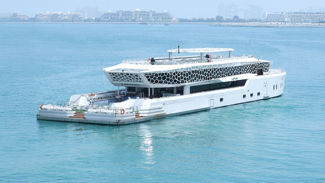 Lotus Mega Yacht cruising in Dubai Marina with cityscape in the background.